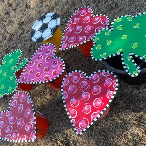 May include: Five painted metal heart and shamrock shapes with black and white trim. Each shape is placed on top of a plastic bucket.