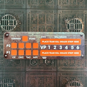 Peut inclure: Un composant de jeu de société rectangulaire avec du texte orange et blanc sur un fond métallique. Le texte comprend "TURNING", "POINT", "VP 1 2 3 4 5 6" et "PLACE TEAM KILL GRADE STRIP HERE". Le fond a un motif répétitif.