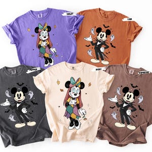 May include: Five colorful t-shirts featuring cartoon characters. The shirts are in violet, yam, ivory, pepper, and espresso colors. The designs include Minnie Mouse and Jack Skellington from The Nightmare Before Christmas, with Halloween-themed elements.