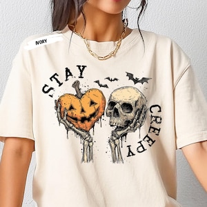 Stay spooky in style with this bold Stay Creepy Halloween Shirt featuring a haunting skull and melting jack-o’-lantern heart design. Perfect for lovers of gothic fashion, spooky season vibes, and creepy cute aesthetics, this skull and pumpkin tee is the ultimate Halloween staple.