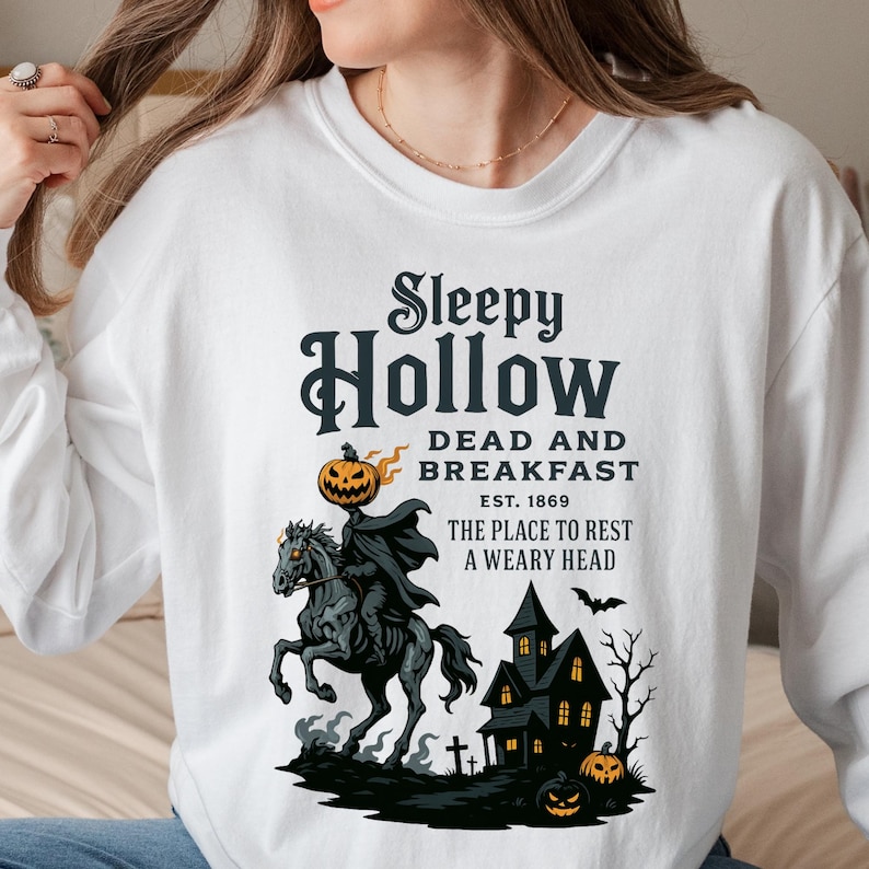 "Sleepy Hollow Halloween shirt featuring a vintage-style Headless Horseman on a spooky horse holding a jack-o'-lantern in front of a haunted house with glowing pumpkins and bats. This eerie Halloween graphic tee is printed on a moss green t-shirt and perfect for spooky season, trick-or-treat, horror movie lovers, gothic fall fashion, haunted house fans, or those searching for a unique October outfit. Ideal for fall events, pumpkin patches, or Halloween parties."
