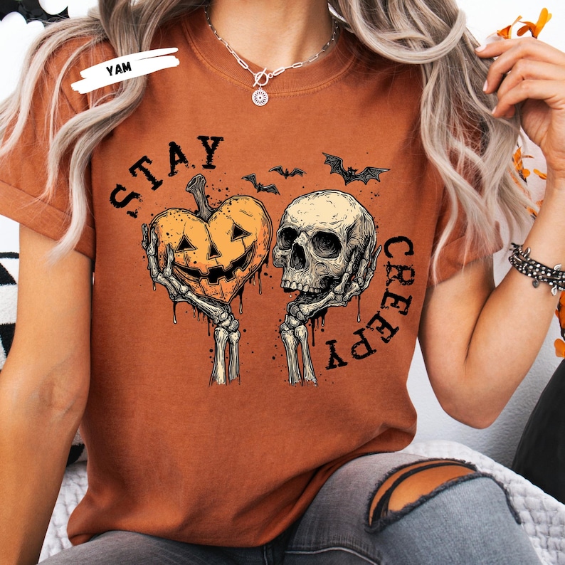 Stay spooky in style with this bold Stay Creepy Halloween Shirt featuring a haunting skull and melting jack-o’-lantern heart design. Perfect for lovers of gothic fashion, spooky season vibes, and creepy cute aesthetics, this skull and pumpkin tee is the ultimate Halloween staple.