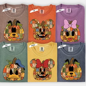 Puede incluir: Seis camisetas Comfort Colors en varios colores, cada una con un diseño de calabaza con la cara de un personaje de Disney. Los personajes incluyen a Mickey Mouse, Minnie Mouse, el Pato Donald y Goofy. Las camisetas están etiquetadas con colores como Espresso, Yam, Berry, Moss, Mustard y Pepper.
