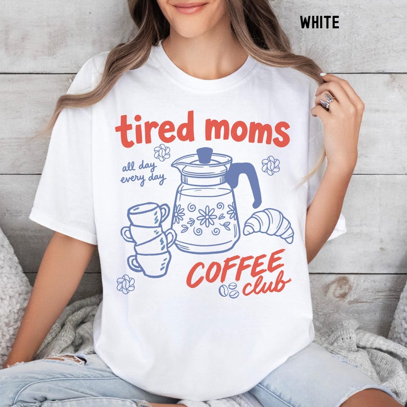Vintage style graphic t-shirt featuring coffee pot, stacked cups, croissant, and playful tired moms coffee club text in soft pastel colors for moms. Printed on Comfort Colors t-shirt in White.