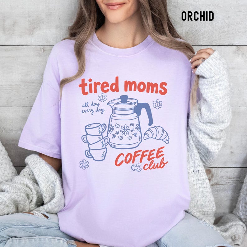 Vintage style graphic t-shirt featuring coffee pot, stacked cups, croissant, and playful tired moms coffee club text in soft pastel colors for moms. Printed on Comfort Colors t-shirt in Orchid.