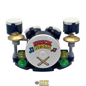 May include: A miniature drum kit constructed from plastic bricks. The central drum features the text "BRICK BEATS" and crossed drumsticks. The set includes additional drums, cymbals, and green and yellow detailing.