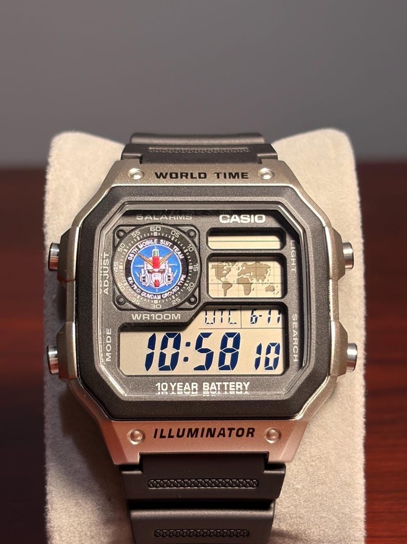 Puede incluir: Un reloj digital Casio con caja negra y plateada y correa negra. La esfera del reloj muestra la hora, la fecha y las funciones de hora mundial. El reloj tiene el texto "10 YEAR BATTERY" e "ILLUMINATOR".