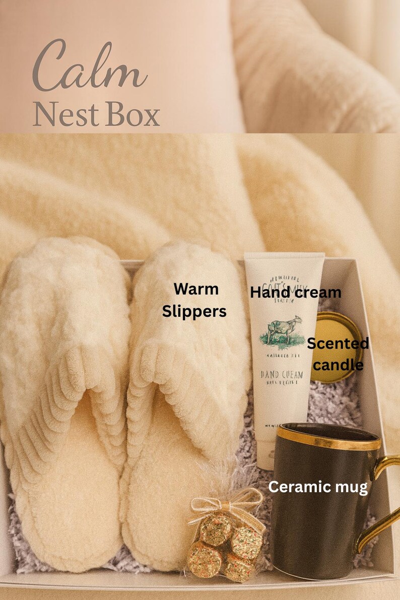 May include: A gift box labeled "Calm Nest Box" containing cream-colored warm slippers, hand cream, a scented candle, a ceramic mug, and a small bag of treats. The mug has a gold handle and trim. The box is filled with shredded paper.