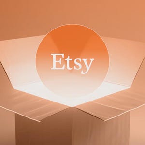 K&ouml;nnte beinhalten: Ein Karton mit ge&ouml;ffneten Klappen, der ein helles Licht und eine kreisf&ouml;rmige Grafik mit dem Wort "Etsy" in Wei&szlig; zeigt. Der Hintergrund ist ein Farbverlauf in Oranget&ouml;nen.