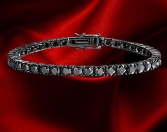 May include: A black tennis bracelet with a clasp, set against a red background. The bracelet is made of black gemstones, and the clasp is silver. The bracelet is a piece of jewelry.