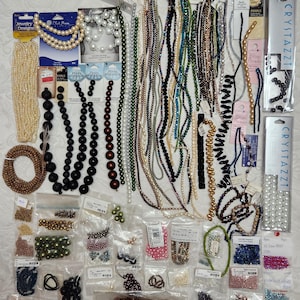May include: A large collection of assorted jewelry making supplies including numerous strands of multi-colored beads, pearls, and crystals. The assortment features various loose beads packaged in clear plastic bags and several retail-packaged bead sets.