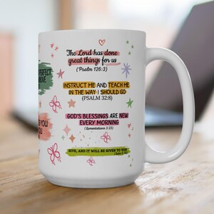 Puede incluir: Taza de cerámica blanca con texto inspirador y detalles coloridos. La taza presenta frases como "El Señor ha hecho grandes cosas por nosotros" y "Las bendiciones de Dios son nuevas cada mañana". Elementos decorativos: estrellas y mariposas.