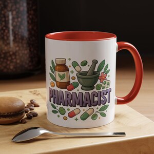 Puede incluir: Taza de cerámica blanca con interior y asa rojos, con una colorida ilustración para farmacéuticos. El diseño incluye un mortero y una maja, pastillas y la palabra "PHARMACIST" en morado.