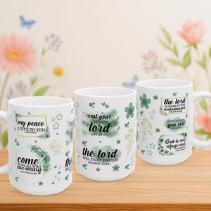 Puede incluir: Tres tazas de cerámica blanca con citas inspiradoras y diseños florales. Las tazas presentan frases como "mi paz os doy" y "el Señor luchará por vosotros". Acentos verdes y dorados decoran las tazas, que están sobre una superficie de madera.