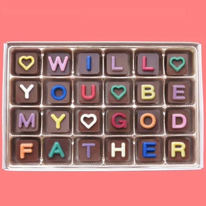 May include: A box of chocolate candies spelling out "Will you be my God Father" with colorful letters and hearts.