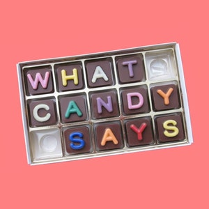 May include: A box of chocolate squares with the letters "WHAT CANDY SAYS" spelled out in colorful frosting.