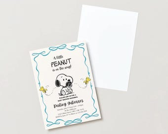 May include: Baby shower invitation featuring Snoopy with the text "A little PEANUT is on the way!". The invitation has a light blue border and includes event details. A blank white card is next to the invitation.