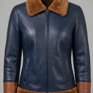 Może przedstawiać: Granatowa skórzana kurtka z brązowym kołnierzem, mankietami i obszyciem z kożucha. Kurtka ma zamek błyskawiczny na całej długości i dopasowany krój. Brązowe wykończenie z kożucha zapewnia ciepły kontrast.