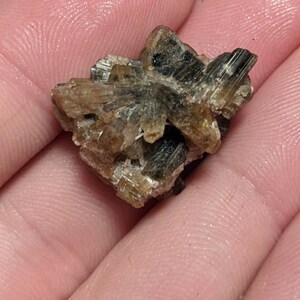 May include: A cluster of brown and green crystals with a rough, natural texture.