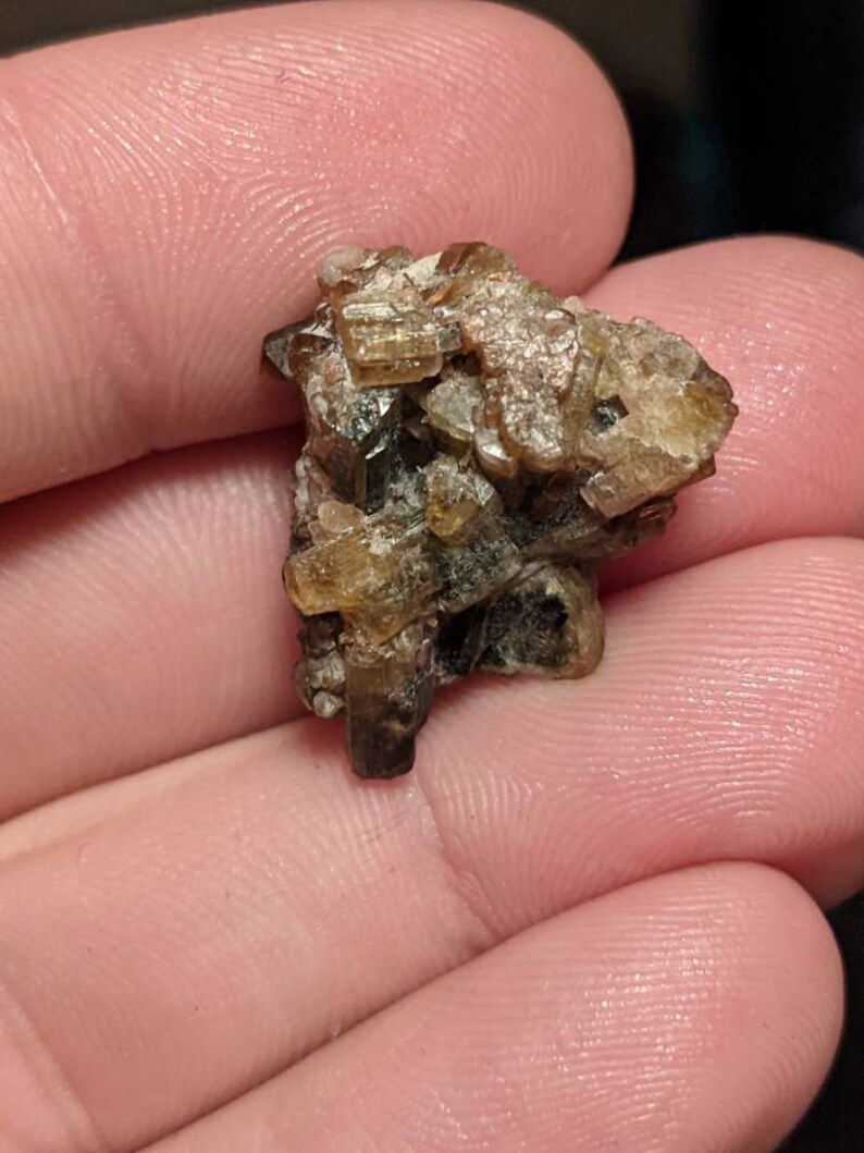 May include: A cluster of brown and gold crystals with a rough, natural texture. The crystals are clustered together in a random, organic shape.