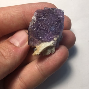 May include: A purple fluorite crystal with white calcite crystals on a matrix. The fluorite is a deep purple color and has a glassy luster. The calcite crystals are white and have a pearly luster.