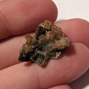 May include: A cluster of brown and gold crystals with a layered, striated texture. The crystals are arranged in a random, organic pattern.
