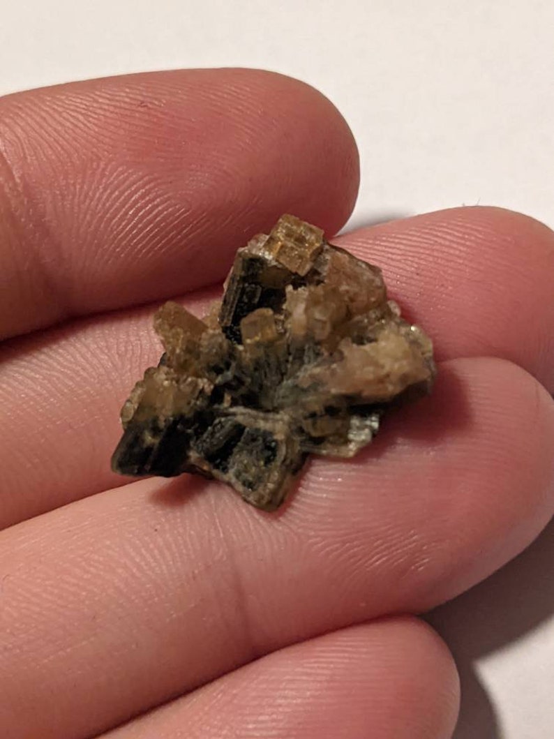 May include: A cluster of brown and gold crystals with a layered, striated texture. The crystals are arranged in a random, organic pattern.