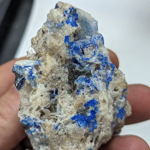 May include: A cluster of white crystals with blue accents. The crystals are arranged in a random pattern and have a rough, natural texture.