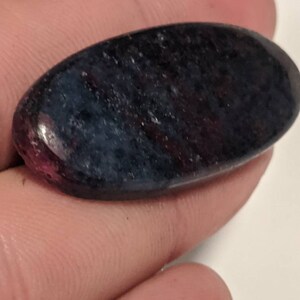 May include: A dark blue and purple oval-shaped gemstone with a speckled pattern.