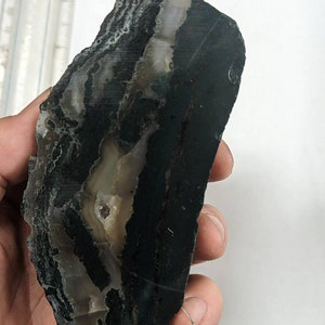 May include: A large, irregularly shaped piece of banded agate with black, white, and grey layers. The agate has a smooth, polished surface.