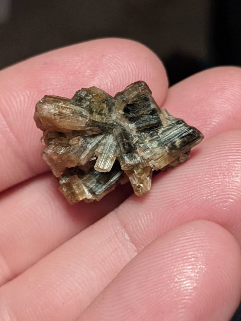 May include: A cluster of brown and green crystals with a starburst shape.