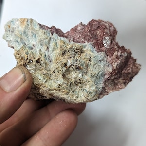 Puede incluir: Primer plano de una roca con una mezcla de cristales azul claro, marrón y blanco. La roca tiene una superficie rugosa y texturizada.