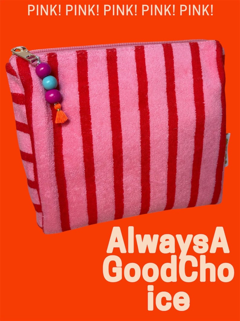 May include: A rectangular zippered pouch made of pink and red striped terry cloth fabric. The zipper pull features two purple beads, one light blue bead, and a small orange tassel. Text reads PINK! PINK! PINK! PINK! PINK! and AlwaysA GoodChoice.