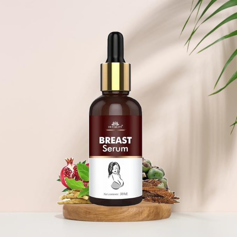 Puede incluir: Una botella de vidrio marr&oacute;n con cuentagotas negro y detalles dorados. La etiqueta dice "BREAST Serum" con la silueta de una mujer. La botella est&aacute; sobre un soporte de madera, con una granada y otros elementos bot&aacute;nicos en el fondo. Contenido neto: 30 ml.
