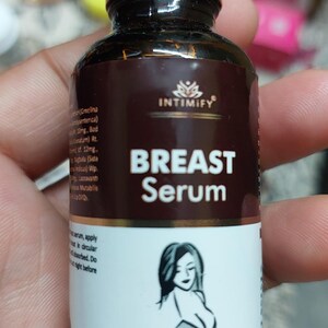 Puede incluir: Una botella marr&oacute;n de "BREAST Serum" con tapa dorada, con la silueta de una mujer. La etiqueta incluye la marca "INTIMIFY" y el texto "Net contents: 30ML".