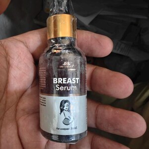 Puede incluir: Una peque&ntilde;a botella oscura de Suero para Senos Intimify con tapa dorada. La etiqueta presenta el nombre del producto y una ilustraci&oacute;n de una mujer. La botella contiene 30 ml de suero.