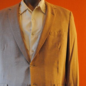 May include: A gray and brown blazer with a button-up shirt underneath. The blazer has a single-breasted closure and two pockets on the front.