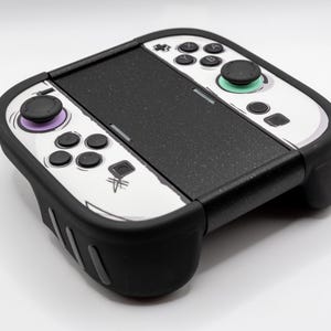 Può includere: Controller di gioco in bianco e nero con accenti viola e verdi. Il controller ha una sezione centrale nera e lati bianchi con pulsanti neri e un joystick nero. Il controller è progettato per il gioco.