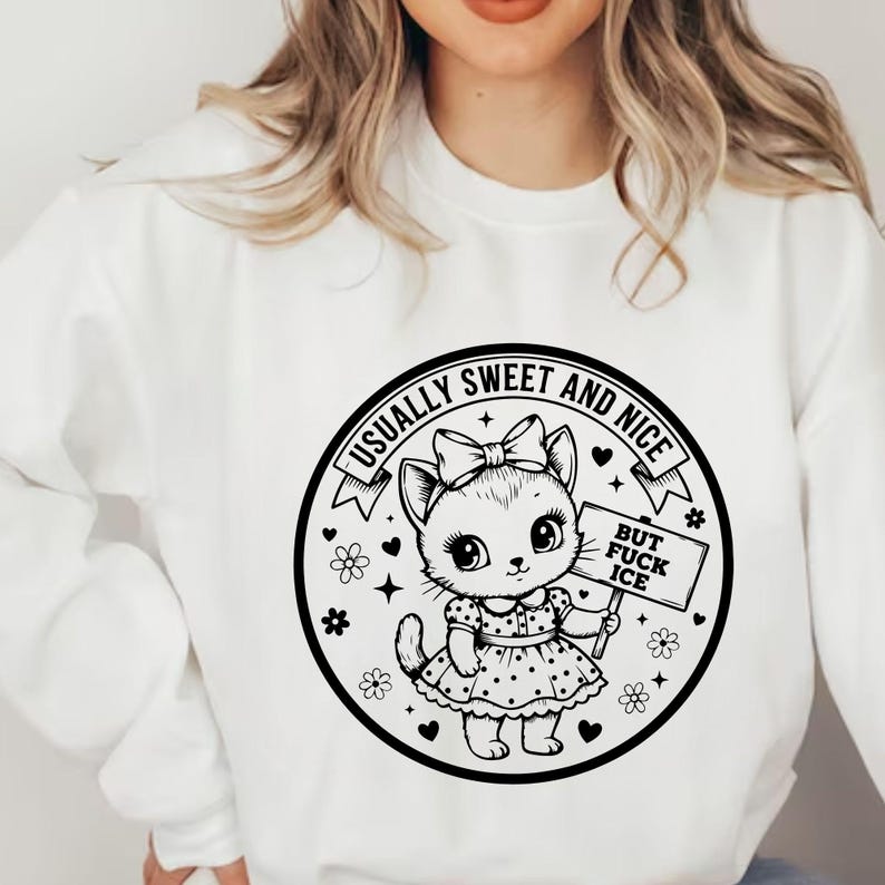 May include: White sweatshirt featuring a black and white graphic of a cute cat with a bow, holding a sign that reads "BUT FUCK ICE". The graphic is surrounded by the text "USUALLY SWEET AND NICE".