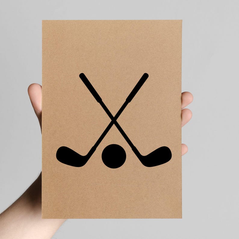 May include: A brown card with a black graphic of two crossed golf clubs and a golf ball. The image is held by a hand against a neutral background. The design is simple and bold.