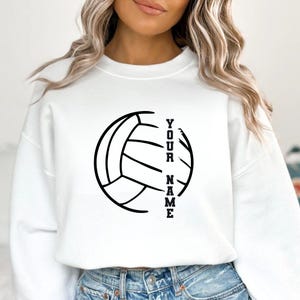 Op de afbeelding: Witte sweatshirt met een zwarte volleybalafbeelding en de tekst "YOUR NAME" verticaal uitgelijnd. Het ontwerp is strak en opvallend, geschikt voor volleybalfans. Een casual kledingstuk.
