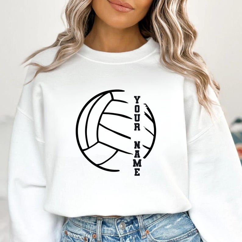Op de afbeelding: Witte sweatshirt met een zwarte volleybalafbeelding en de tekst "YOUR NAME" verticaal uitgelijnd. Het ontwerp is strak en opvallend, geschikt voor volleybalfans. Een casual kledingstuk.