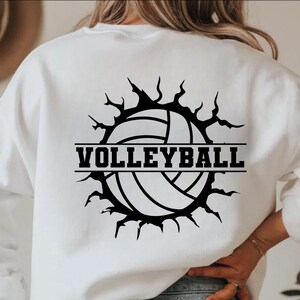 May include: White sweatshirt with a black volleyball graphic. The graphic features a volleyball design with the word "VOLLEYBALL" in bold, black letters. The design has a torn-edge effect around the volleyball.