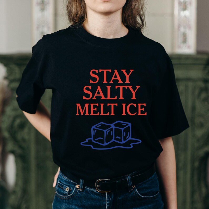 May include: Black t-shirt with the red text "STAY SALTY MELT ICE" above a blue illustration of two ice cubes melting. The shirt is a crew neck style.
