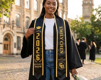 May include: A smiling graduate in a black graduation gown and sash. The sash reads "Class of 2026, Biology Major" and "Emily Chen, City University." She holds a bouquet of flowers. The background shows a university building.