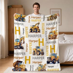 Op de afbeelding: Een witte fleece deken met een herhalend patroon van gele bouwvoertuigen, waaronder graafmachines, kiepwagens en bulldozers. Het ontwerp bevat de naam Harper in verschillende lettertypes en kleuren, samen met de grote hoofdletter H.