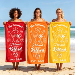 Op de afbeelding: Drie rechthoekige strandhanddoeken in rood, oranje en geel, elk met witte grafische prints van een cocktail, palmboom, schelpen, slippers en een strik. De tekst luidt: the summer est. 2026 I turned Retired Mrs. White.