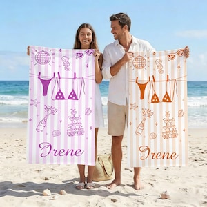 Könnte beinhalten: Ein Paar hält zwei gestreifte Strandtücher an einem Sandstrand. Eines ist rosa und das andere beige. Jedes Handtuch hat ein Bikini-, Champagner- und Discokugel-Design. Der Name "Irene" ist auf jedem Handtuch aufgedruckt.