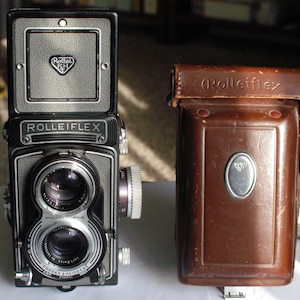 Appareil photo reflex à double objectif Rolleiflex modèle T pour des images 6 x 6 cm sur film 120 rouleaux.  Comprend un étui, un pare-soleil, un bouchon d'objectif et 3 ensembles de gros plans