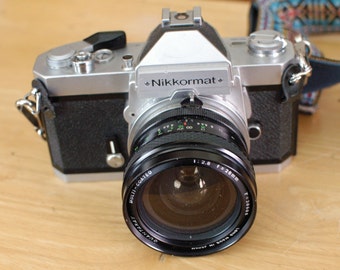 Nikon Nikkormat FT2 chrome finish 35mm SLR Camera with 28mm f2.8 Quantaray wide angle lens & offbrand strap.